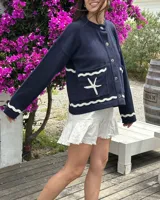 Cárdigan de tejido punto color azul marino, con diseño náutico bordado en la espalda que incluye un velero rojo y blanco, olas blancas y la inscripción "le port" en blanco.