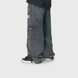 Pantalón cargo de jean color negro con efecto lavado, de corte ultra baggy y diseño holgado. Presenta bolsillos laterales tipo cargo con solapa y un detalle bordado en la parte superior delantera.