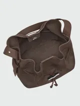 Cartera tipo bucket bag de hombro Longchamp modelo Le Roseau Velvety M, confeccionada en cuero marrón con textura de gamuza. Cuenta con correa de hombro ajustable y detalle de cierre de barrita metálica con el distintivo de la marca.