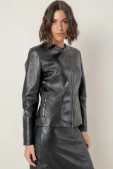 Campera de cuero color camel, con cuello redondo, cierre frontal y detalles de tachas metálicas en el cuello y bolsillos laterales.