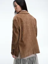 Blazer de pana color marrón con solapas clásicas, cierre frontal de dos botones y bolsillos laterales con solapa.