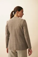 Chaqueta corta color beige, entallada, con escote en V, manga larga y bolsillos escondidos. Cierre frontal con lazo fijo. Confeccionada en lana fina sin teñir. Diseño exclusivo de Don Baez.