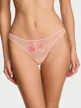 Tanga de malla elástica color salmón, con tiro bajo, ribete de picot y detalle de rosas bordadas en el frente.