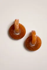 Aros colgantes de diseño circular, compuestos por dos aros entrelazados de resina con efecto marmolado en tonos ámbar.