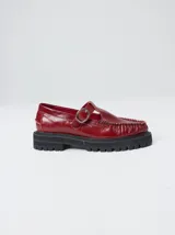 Zapato tipo guillermina de cuero color bordó, con diseño de mocasín, hebilla metálica y suela de goma con plataforma dentada.