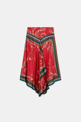 Falda midi de tiro medio con bajo asimétrico y cierre posterior con cremallera oculta. Presenta un diseño fluido con estampado de cadenas, borlas y motivos ecuestres sobre fondo rojo, con bordes en tonos verde y azul.