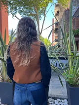 Chaleco de cuero en la parte delantera y tejido de hilo en la espalda, con diseño abierto en la parte frontal y corte corto.