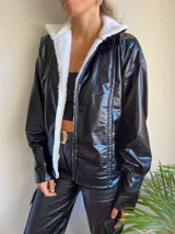 Campera negra de cuero sintético con interior de corderito blanco, corte holgado y mangas largas con puños elásticos.