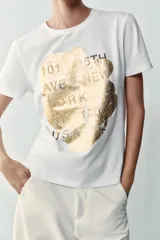 Camiseta blanca de manga corta y cuello redondo, con detalle de estampa central metalizada de efecto texturizado y diseño regular fit.