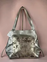 Bolso tipo tote Chabas confeccionado en cuero genuino color plateado, con un bolsillo frontal texturizado en tonos metalizados y doble asa superior para el hombro.