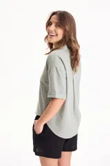 Camisa de lino color beige, de manga corta, con cuello camisero, bolsillos delanteros con solapa y cierre frontal con botones de madera.