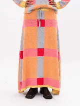 Pollera larga de tejido de punto con diseño geométrico a cuadros en tonos naranja, gris, rojo y rosado, con cintura elástica ajustable mediante cordón.