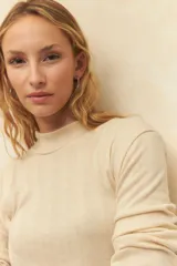 Polera color crema de algodón con cuello alto y mangas largas.