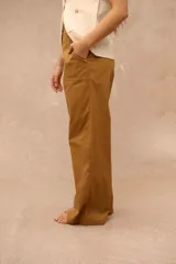 Pantalón de corte ancho y holgado, color ocre, con bolsillos frontales aplicados y costuras pespunteadas visibles.
