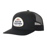 Gorra trucker negra de seis paneles con corona media, visera plana y parte trasera de malla. Cuenta con un parche frontal con el logotipo y el texto 'Katin Customs USA Est. 1954'.