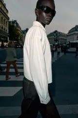 Camisa corta blanca de popelín con cuello solapa decorado con abalorios joya, manga larga y cierre frontal de botones.