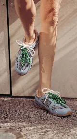 Zapatillas urbanas de cuero celeste y mesh gris, con suela de goma y doble juego de cordones intercambiables en color verde y blanco.