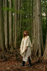 Ruana color crema de tejido de punto grueso con flecos en el borde inferior.