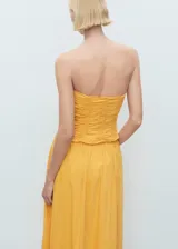 Top bandeau amarillo con diseño fruncido en el cuerpo, sin mangas y cierre de cremallera en la espalda.