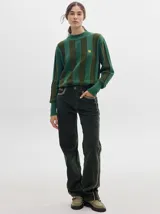 Pantalón de pana roja con corte holgado y tiro medio. Presenta una línea dorada a lo largo de la pierna.