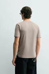 Camiseta de corte ajustado confeccionada en tejido de algodón con elasticidad, cuello redondo y manga corta.