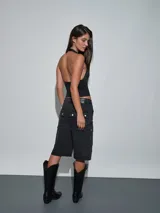 Top halter negro con detalle de tira y hebilla metálica en el hombro, con escote en V pronunciado y corte ajustado.