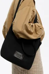 Bolso shopper mediano de hombro Bimba Y Lola confeccionado en tejido Flyknit de estructura blanda y diseño de red. Cuenta con doble asa de mano, asas largas para el hombro, cierre de cordón ajustable y etiqueta frontal con el logo de la marca.
