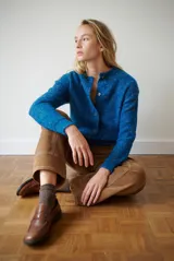 Saco de punto color azul con detalles de motas de colores, cuello redondo y cierre frontal con botones.