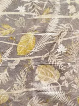 Mantel rectangular grande de algodón con estampado botánico en tonos dorados sobre fondo marrón.