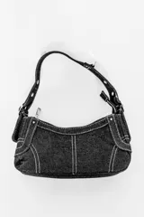 Cartera negra de jean con costuras blancas, cierre superior y correa de hombro ajustable.
