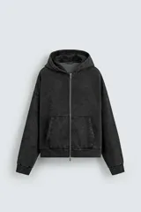 Sudadera con capucha y cierre de cremallera, de corte relajado (relaxed fit), confeccionada en algodón con interior afelpado. Presenta bolsillos frontales tipo canguro y acabados en rib. El tejido tiene un efecto lavado que le da un color negro desgastado.