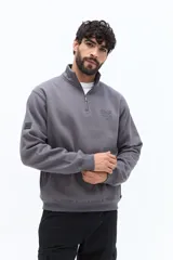 Buzo de algodón color terracota, con cuello alto y cierre parcial frontal. Presenta puños y cintura ajustados, bolsillos laterales y un pequeño logo bordado en el pecho.