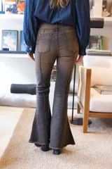 Jean de denim azul de corte acampanado, con costuras frontales en relieve tipo alforza y terminación desmechada en el bajo.