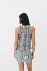 Top sin mangas de tejido liviano con estampado floreado en tonos azules y blancos, diseño con volados escalonados en el pecho y silueta evasé.
