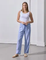 Pantalón largo de lino estampado a rayas verticales celestes y blancas. Tiene pretina ancha elastizada con lazo ajustable.
