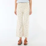 Pantalón de corte wide leg en color crudo con estampado floral pequeño, tiro alto, bolsillos frontales y cierre con botón y cremallera.
