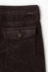 Pantalón acampanado de pana suave de algodón, color marrón oscuro. Presenta un corte ajustado de cintura a cadera y acampanado desde la rodilla al bajo. Es un modelo de tiro bajo con cierre y botón, con bolsillos abiertos delanteros y bolsillos traseros con solapa y botón.