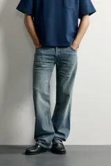 Jeans flare fit de denim rígido en color azul con efecto lavado. Presentan tiro medio, diseño de cinco bolsillos y cierre frontal con cremallera y botón.
