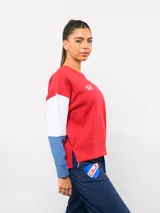 Buzo de cuello redondo con diseño de bloques de color en rojo, blanco y azul. Presenta el logo de Umbro y el escudo del Club Nacional de Football bordados en el pecho.