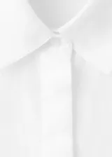Camisa de lino blanca de corte recto, con cuello camisero, mangas largas y cierre frontal oculto de botones.