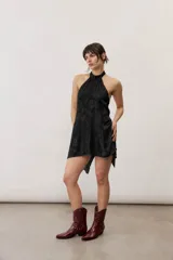 Top negro de satén con escote halter, diseño sin mangas y bajo asimétrico con terminación en punta.