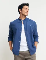 Camisa de cuello mao y manga larga, confeccionada en una mezcla de lino y algodón. Presenta un diseño de corte recto con botones en tono natural y un bolsillo pequeño en el pecho.