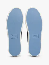 Zapatillas bajas de lona azul marino con costuras blancas contrastantes y suela de goma blanca. Presentan un parche de gamuza celeste en el talón y el logo de Tommy Hilfiger grabado en el lateral.