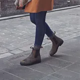 Botas Chelsea Blundstone color marrón rústico con laterales elásticos negros y detalle de perforaciones decorativas.