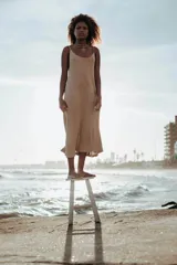 Vestido largo tejido en color dorado con brillo, de breteles finos y escote redondo.