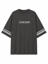 Remera de corte oversize color gris oscuro con efecto lavado, cuello redondo, mangas cortas con doble franja horizontal en color gris claro y estampado frontal con la palabra CHICAGO.