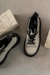 Botas de cuero color beige con suela track negra de goma y cordones gruesos negros. Presentan un diseño de caña baja con costuras visibles y puntera reforzada.