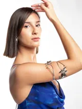 Brazalete plateado rígido con diseño de flores metálicas en los extremos.