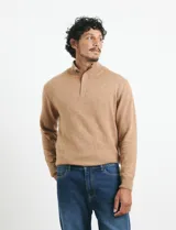Sweater de punto color tostado, con cuello alto y cierre frontal parcial con botones. Diseño de manga larga con puños y ruedo acanalados.