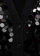 Cardigan negro de punto con cuello en pico y cierre frontal de botones. Presenta un diseño corto con mangas largas y puños elásticos, decorado íntegramente con lentejuelas circulares brillantes.